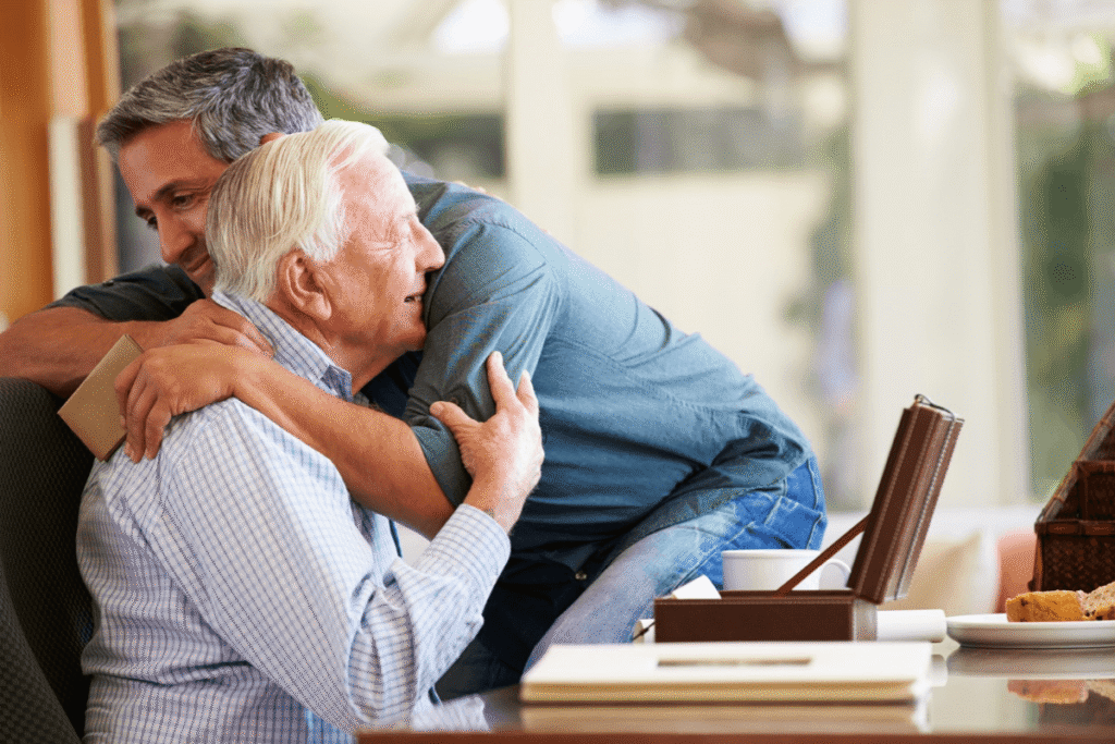 An adult son offering comfort to his elderly father.